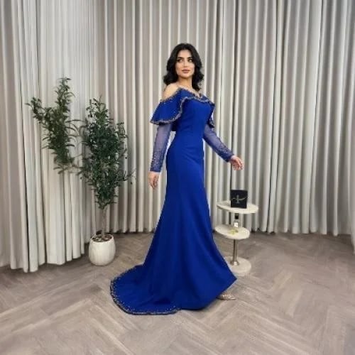 فستان سهرة أزرق ملكي بفتحة أمامية وذيل وأكمام شفافة.