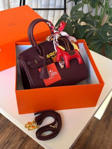 حقيبة Hermes عنابي وأكسسوارات ذهبية وشرائط حمراء ف...