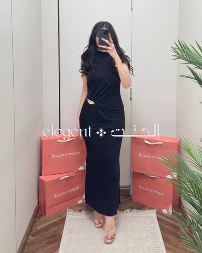 فستان أسود طويل فخم بكسرات أنيقة وبروش ذهبي