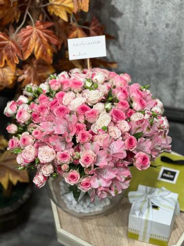 فازة ورد منسقة بتشكيلة متنوعة من الورود بأغصانها ب...