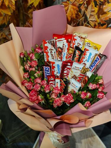 تشكيلة منوعة من الحلويات مرتبة داخل بوكيه مع ورد ب...