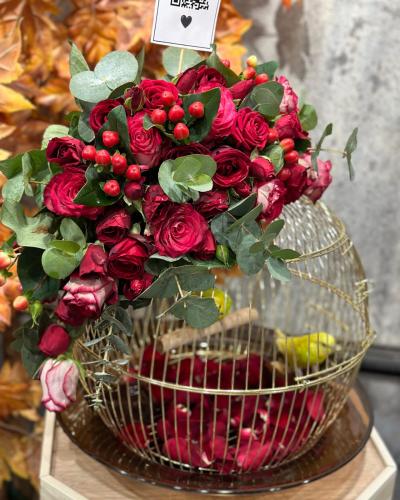 زوج من العصافير في قفص مع تنسيق بتشكيلة من الورود...