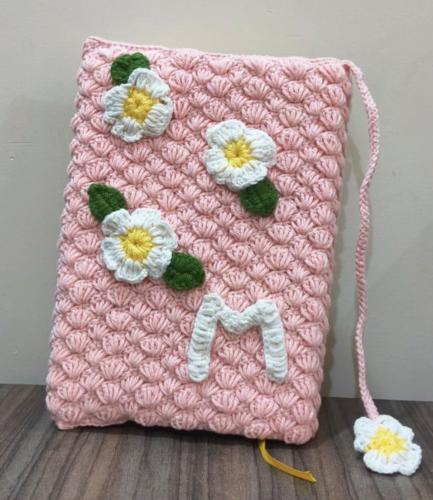 Pink Quran cover with floral decorations and a let...