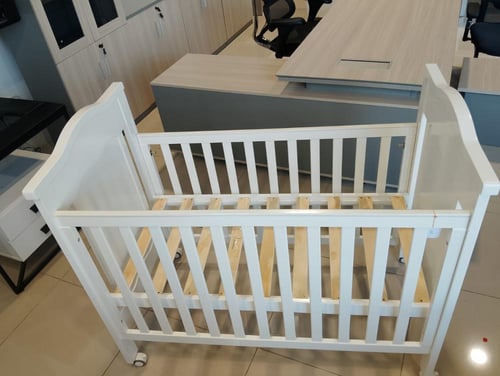 سرير أطفال بتصميم خشبي بعجلات بلون أبيض