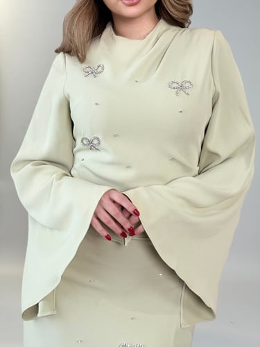 فستان أنيق بأكمام واسعة وتفاصيل ناعمة على شكل فيون...