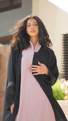 عباية سوداء مع فستان وردي