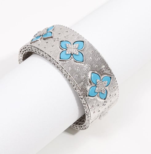 سوار عريض بلون فضي فاخر، بتفاصيل مطرّقة وزخارف زهر...
