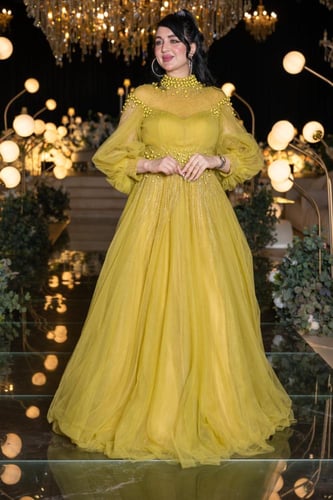 فستان سهرة أصفر بتصميم ملكي وتفاصيل لؤلؤية فاخرة