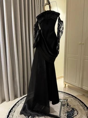 فستان سهرة أسود بتصميم درامي وأكمام شفافة