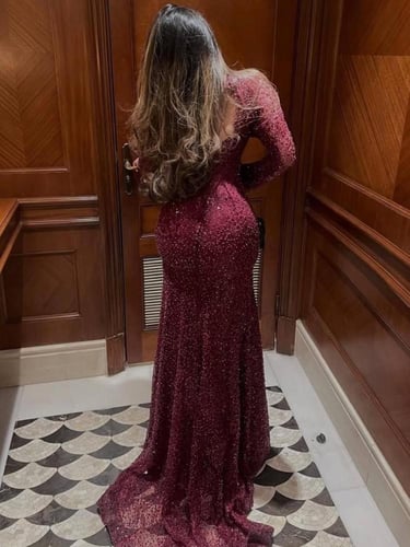 فستان سهرة عنابي بياقة عالية وأكمام طويلة.