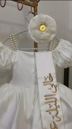 فستان ابيض مزين بالؤلؤ على كتف مع وشاح تطريز
