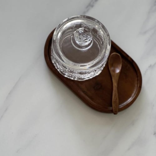 علبة زجاج مع ملعقة وصحن خشبي