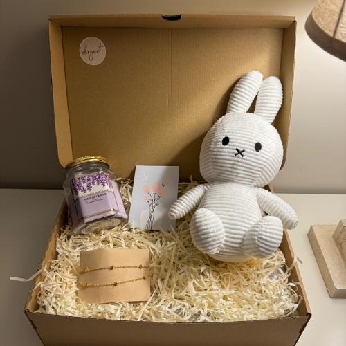 A gift containing: a doll, a candle, a bracelet, a...