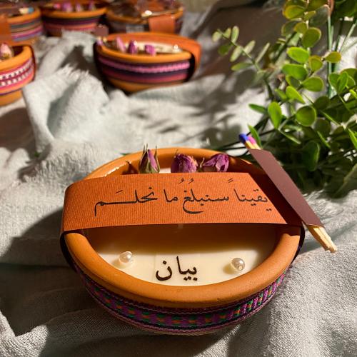 A flower candle with a tag with a phrase