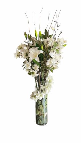 Luxurious artificial flower arrangement inside a tall transparent glass vase with a natural touch