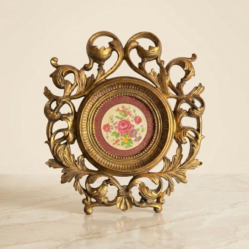 A classic plate made of decorated porcelain with a carved wooden frame in the shape of elegant flowers