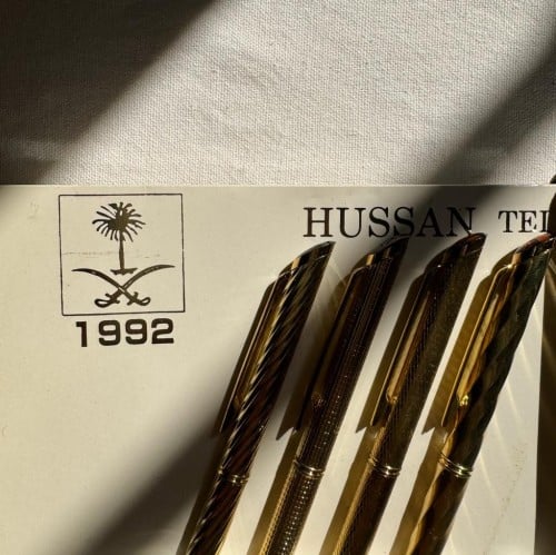 قلم لون ذهبي بتصاميم مختلفه يوجد في اعلاه شعار " س...