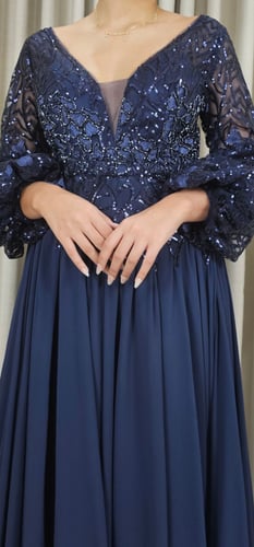 فستان سهرة كحلي مطرز بالترتر مع أكمام شفافة واسعة...