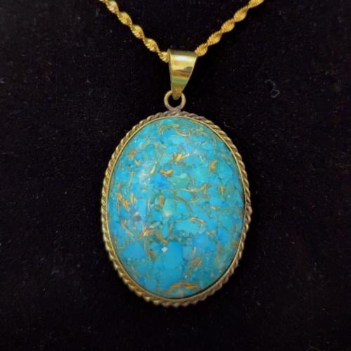 A turquoise pendant with brass chain