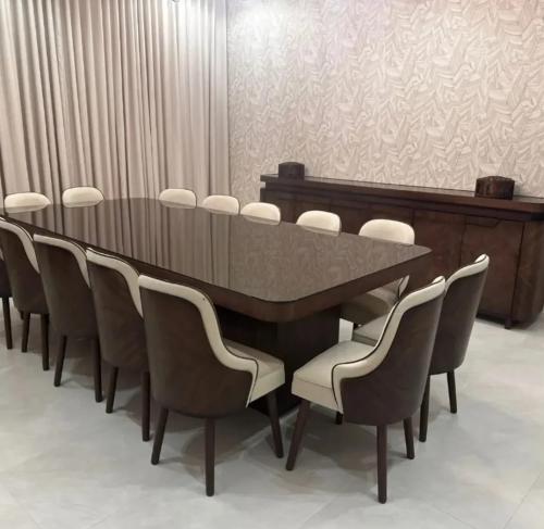 طاولة طعام فاخرة بطابع خشبي داكن مع 12 كرسياً بتصم...