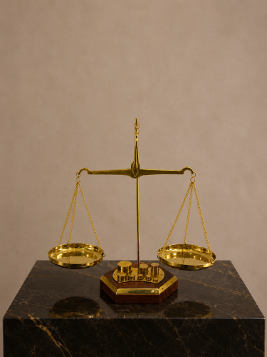 مجسم ميزان العدالة الذهبي على قاعدة رخامية سوداء