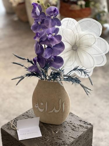 فازة حجرية مع ورد الاوركيد والوردة القماشية