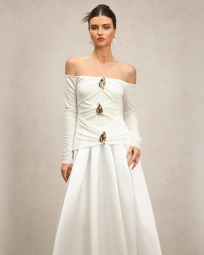 فستان أبيض كريمي بأكتاف مكشوفة وأكمام طويلة