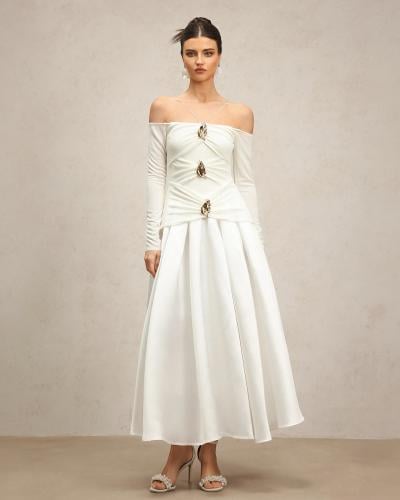 فستان أبيض كريمي بأكتاف مكشوفة وأكمام طويلة