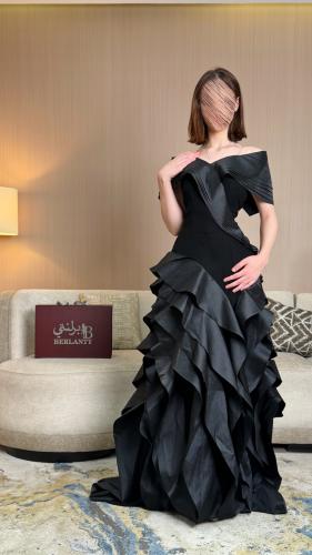 فستان سهرة أسود طويل بكشكش متدرّج وأكتاف مكشوفة