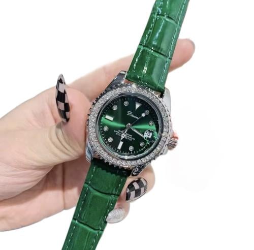A silver watch with a green strap decorated with c...