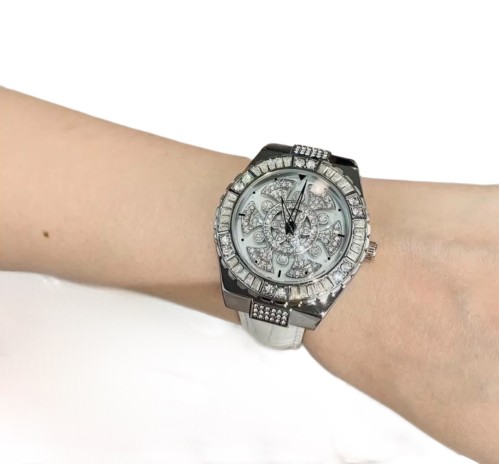 A silver watch with a white strap encrusted with c...