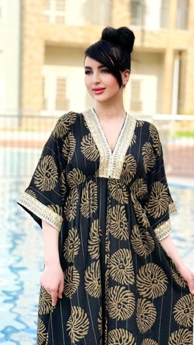 فستان طويل أسود مزخرف بنقوش ذهبية مع تصميم عصري