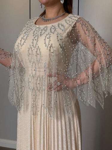 فستان ناعم عاجي فاخر بتطريز كريستالي وأكمام شيفون...