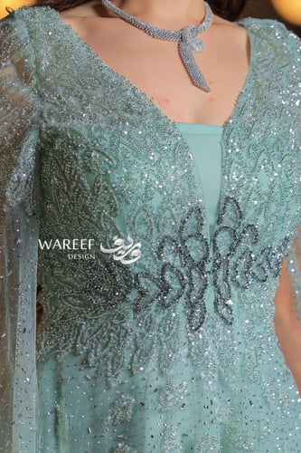 فستان أخضر فاتح طويل مطرز بأكمام شفافة مع ريش فاخر...