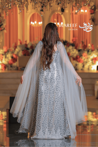 فستان فضي طويل مطرز بالكريستال مع كاب شفاف مرصع