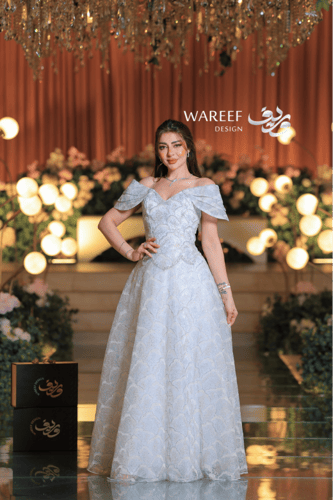 فستان سهرة ملكي فضّي بلمعة كريستالية وتصميم أكتاف...