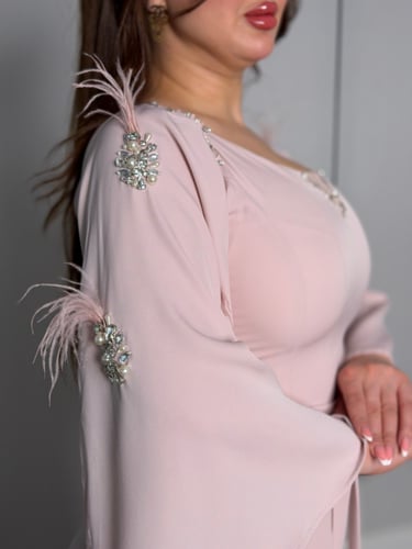 فستان ناعم بلون وردي هادئ بأكمام واسعة وتفاصيل ريش...