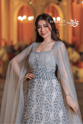 فستان فضي طويل مطرز بالكريستال مع كاب شفاف مرصع