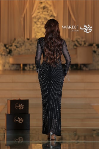 فستان أسود ضيق مزين بخطوط لامعة وأكمام شيفون شفافة