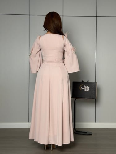 فستان ناعم بلون وردي هادئ بأكمام واسعة وتفاصيل ريش...