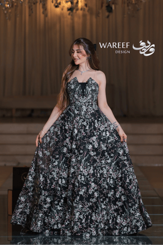 فستان أسود طويل مطرّز بالورود الملونة مع لمسات ترت...