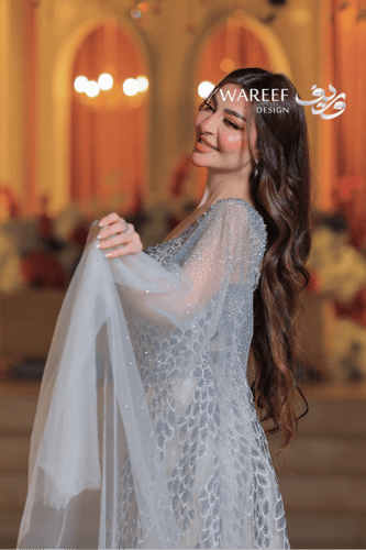 فستان فضي طويل مطرز بالكريستال مع كاب شفاف مرصع