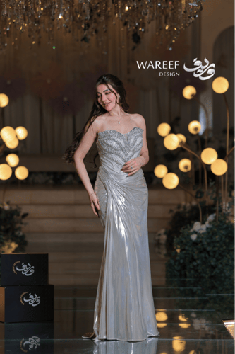 فستان سهرة فضي لامع بتطريز فاخر وقصّة ملتفّة لإطلا...