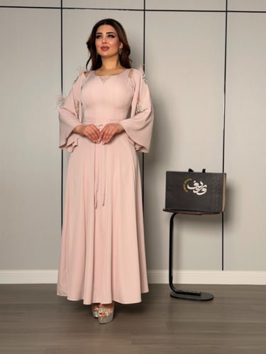 فستان ناعم بلون وردي هادئ بأكمام واسعة وتفاصيل ريش...