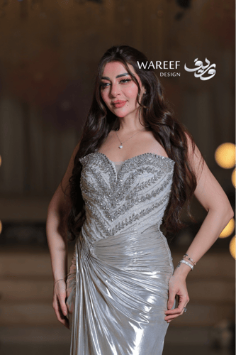 فستان سهرة فضي لامع بتطريز فاخر وقصّة ملتفّة لإطلا...