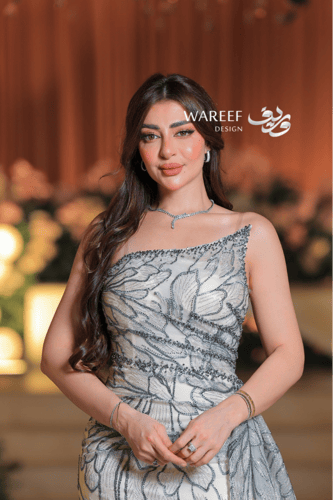 فستان سهرة عاجي فاخر بتطريز زهري لامع وقصّة كتف وا...