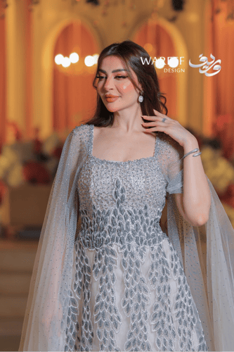 فستان فضي طويل مطرز بالكريستال مع كاب شفاف مرصع