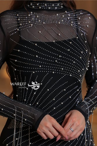 فستان أسود ضيق مزين بخطوط لامعة وأكمام شيفون شفافة