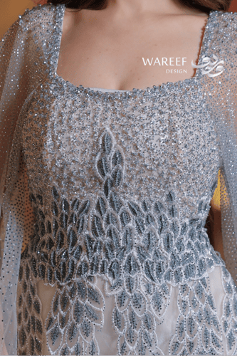 فستان فضي طويل مطرز بالكريستال مع كاب شفاف مرصع