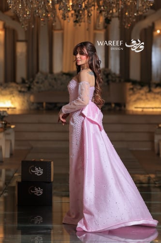 فستان وردي طويل مطرز بلمعة ناعمة مع أكمام شفافة وق...